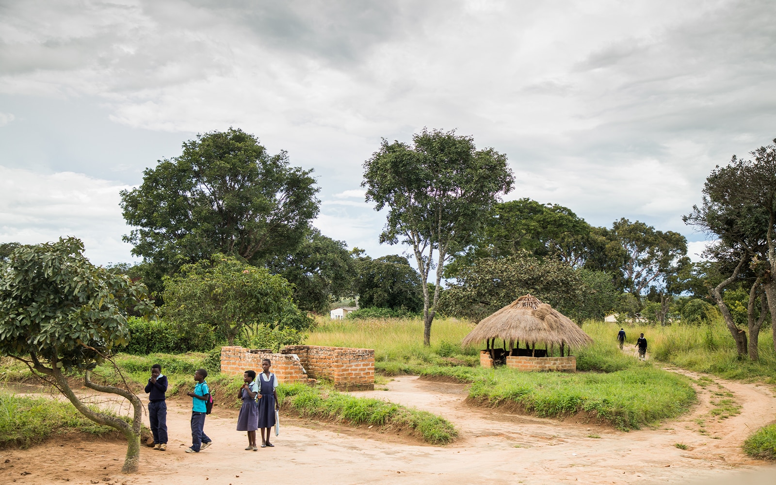 Four children standing outside near hut