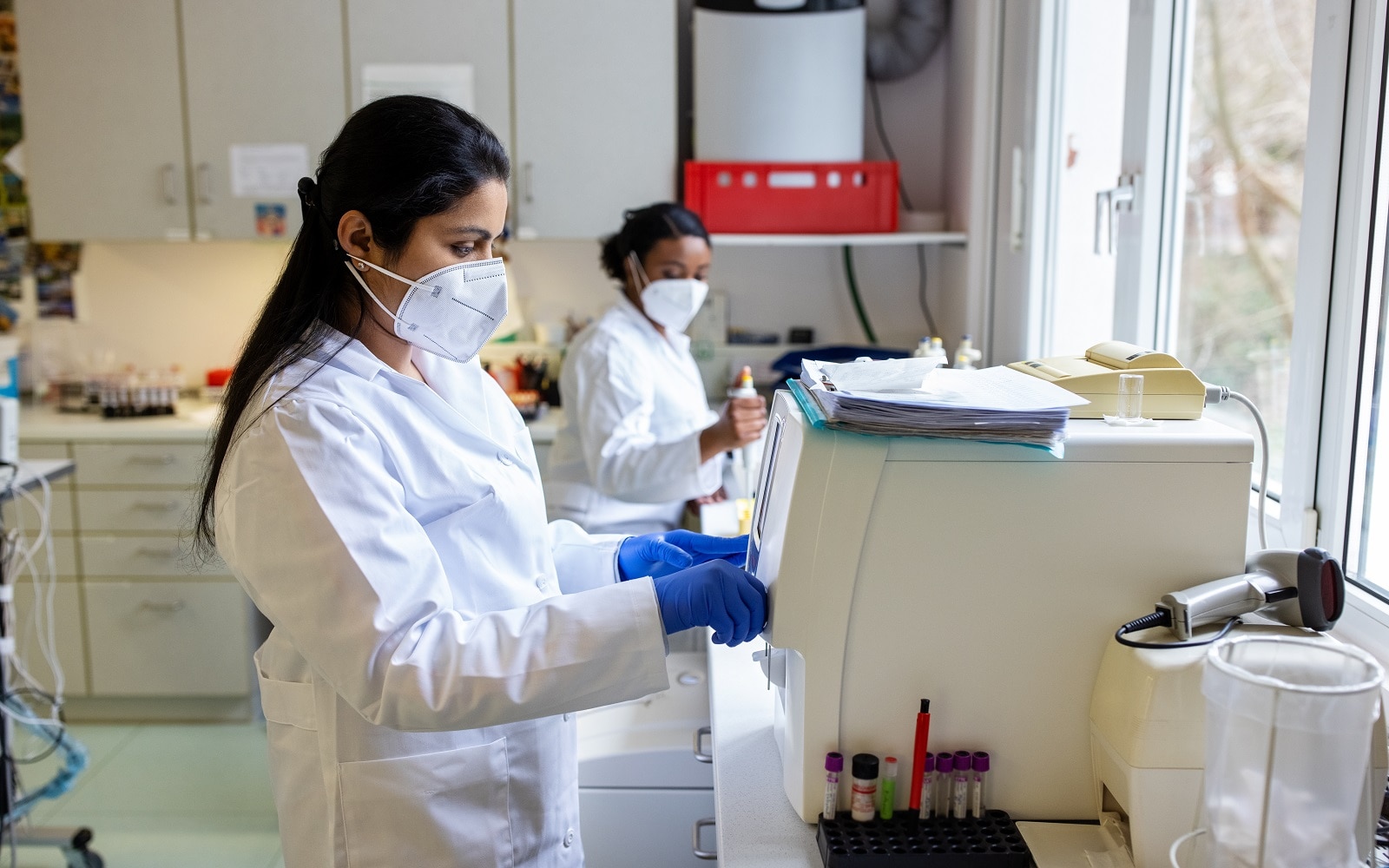 Female scientists using a machine to test samples in a laboratory.